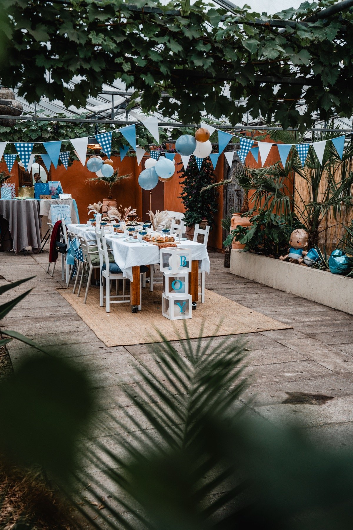 Blauwe slingers en ballonnen boven de babyshowertafel